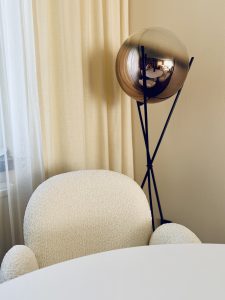 Designer-Stehleuchte vor texturierten Vorhängen als hochwertiges Detail im Interior Styling